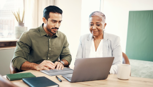 Two professionals reviewing information on a laptop